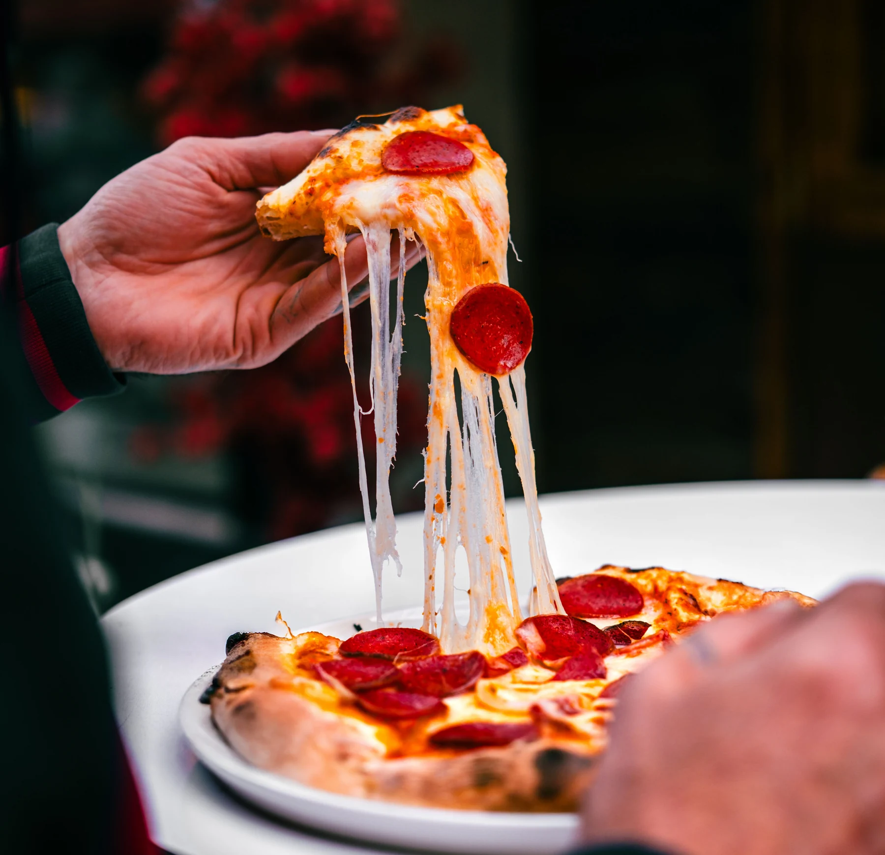 A lifted pizza slice with warm, stretching mozzarella